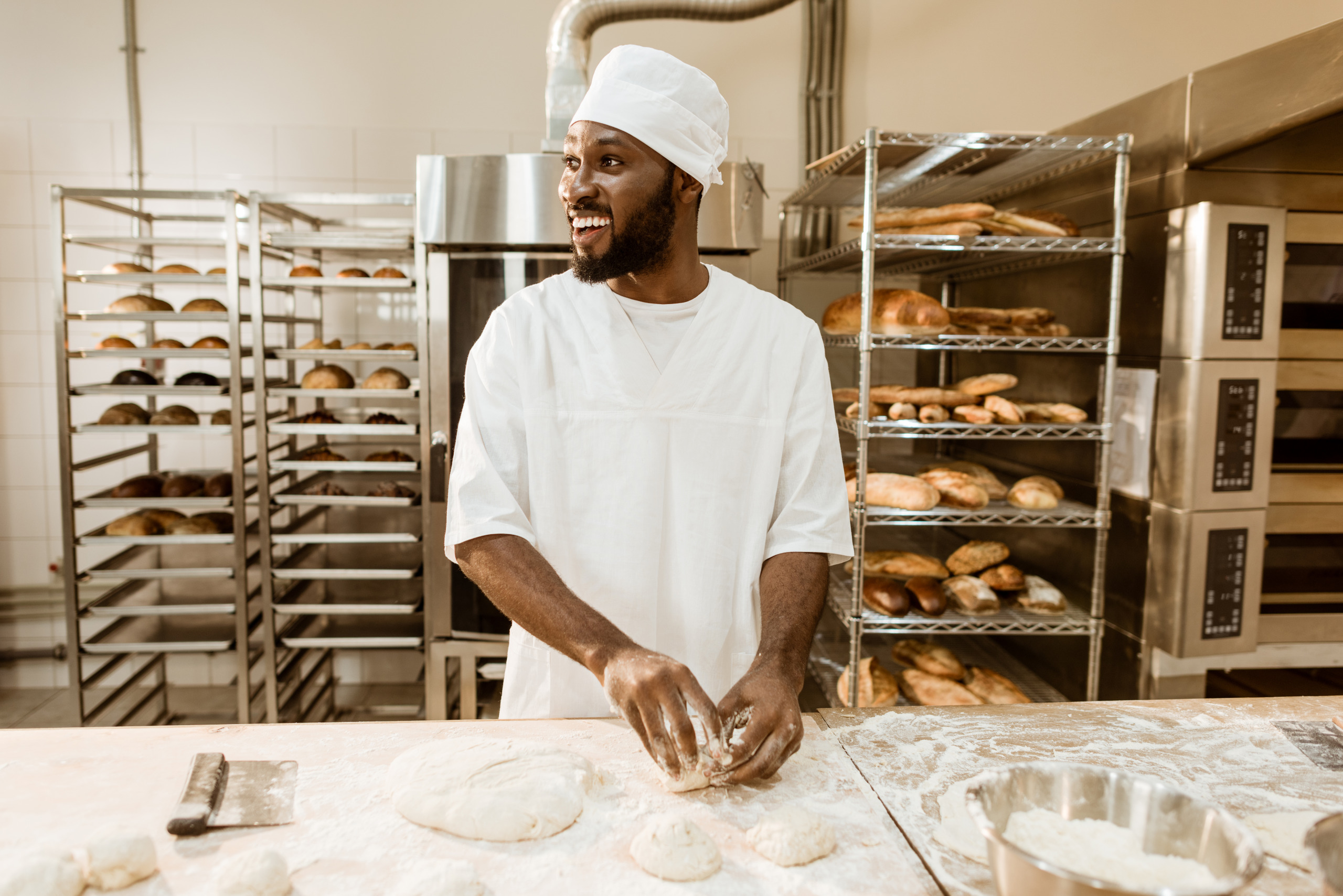 Mitarbeiter in einer Bäckerei formt Brotteig
