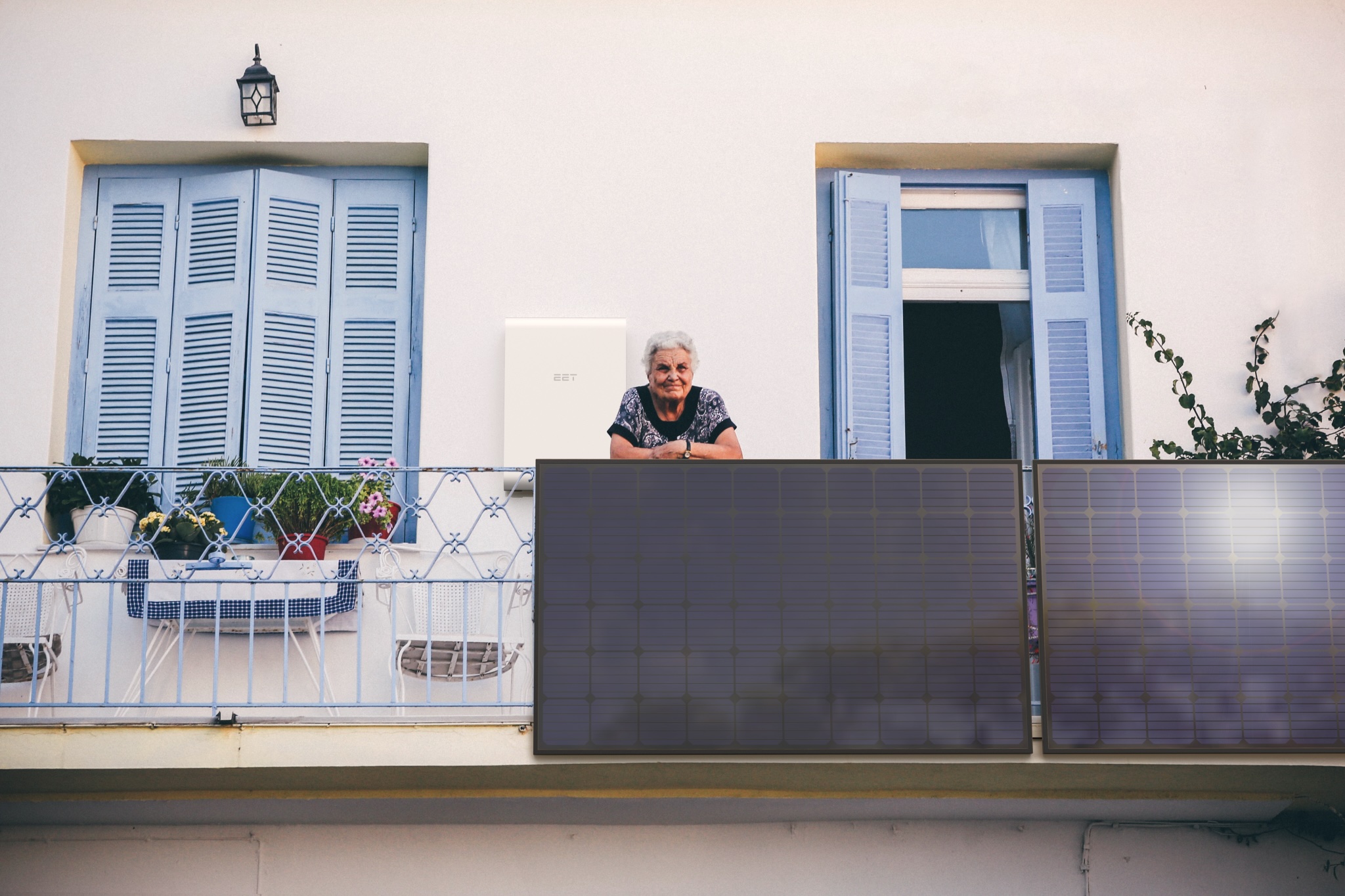 Ältere Frau steht auf Balkon mit Balkonkraftwerk und Speicher