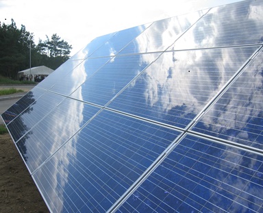 oekostrom AG: Eine Reihe von Solarmodulen im Freien, die die Wolken am Himmel reflektieren.