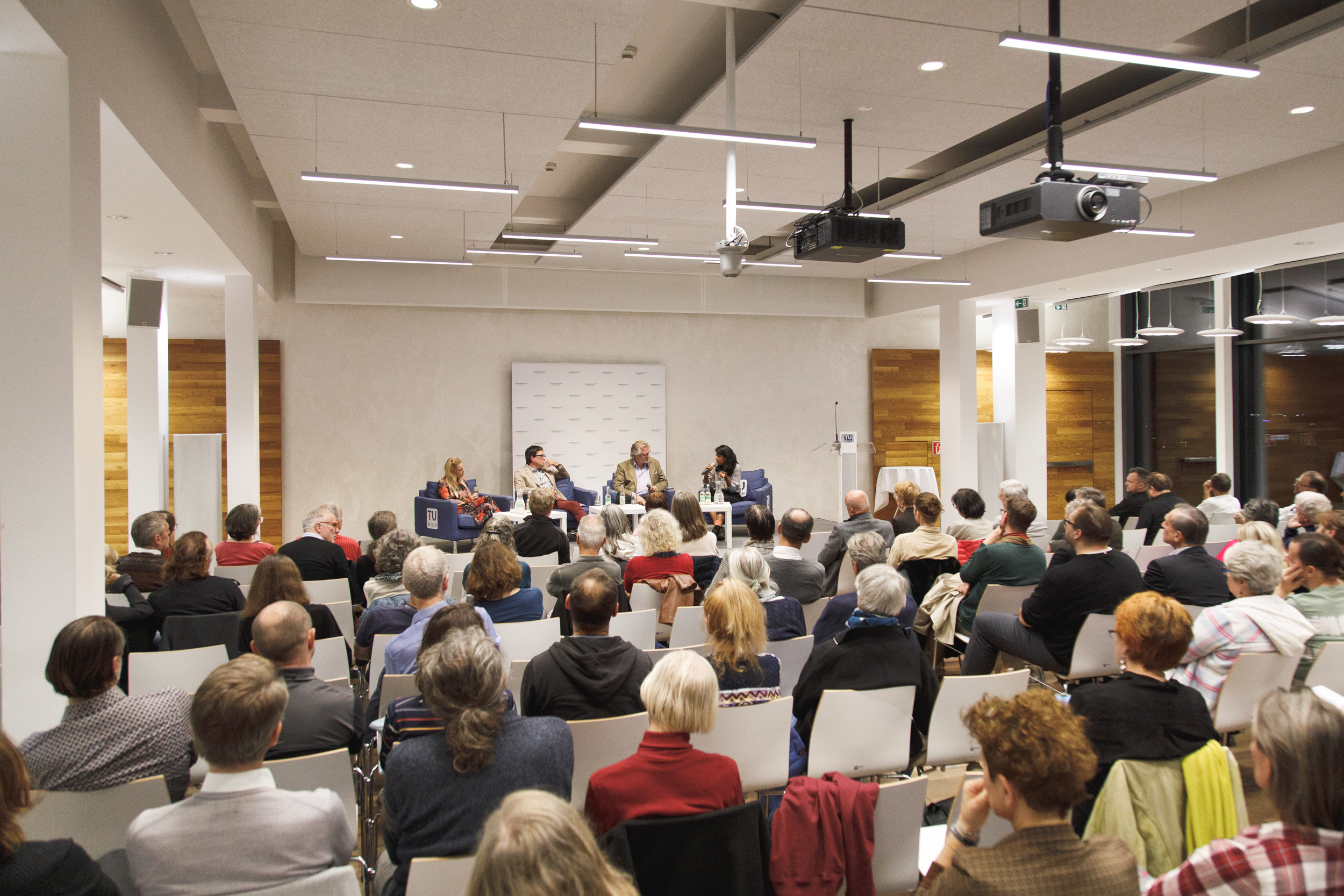 oekostrom AG: Ein vierköpfiges Gremium spricht zu einem Publikum in einem modernen Konferenzraum.