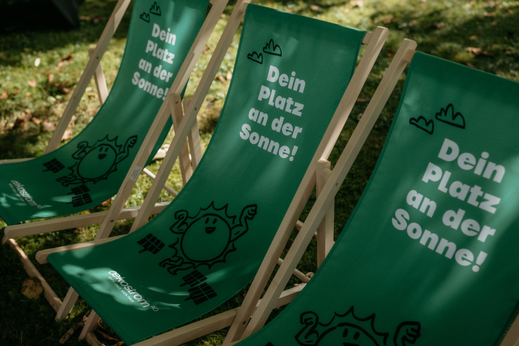Drei grüne Liegestühle im Gras mit dem Aufdruck 