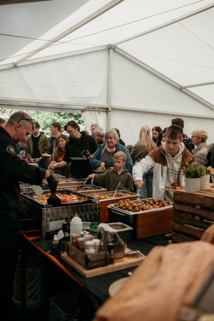 Unter einem großen weißen Zelt bedienen sich die Gäste des Eröffnungsfestes St. Veit an den Buffet-Tabletts.